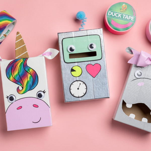 Three ducktape valentine's day card boxes, decorated as a unicorn, a robot and a hippo.