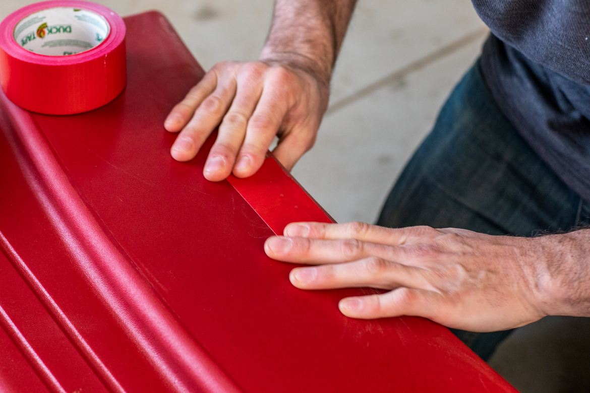 Man repairing red wagon with red duct tape