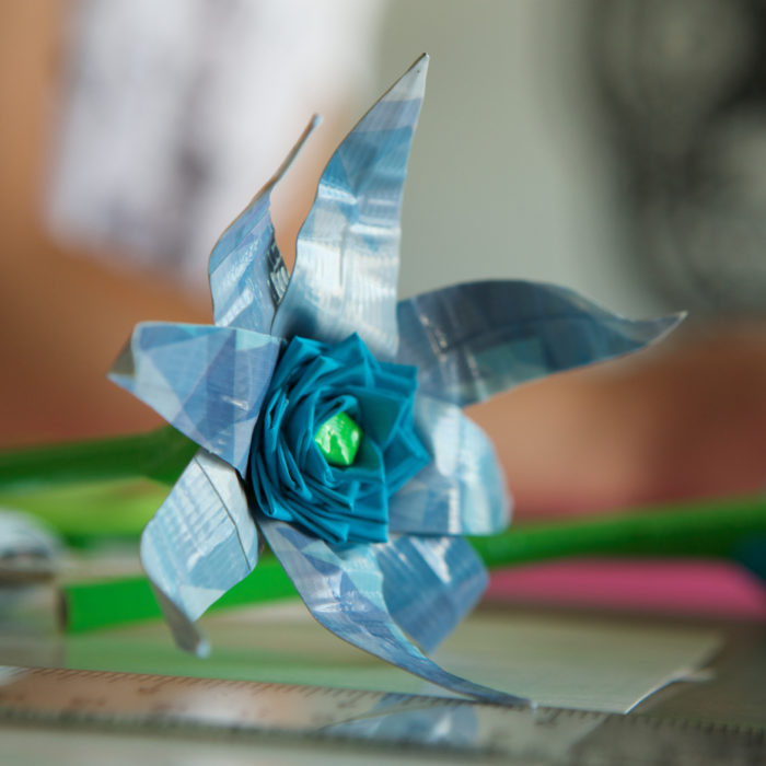 A blue duck tape flower with a green center.