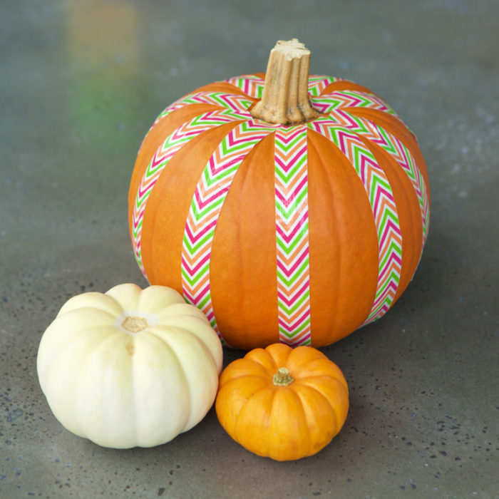 A orange pumpkin with colorful Duck Tape on it.