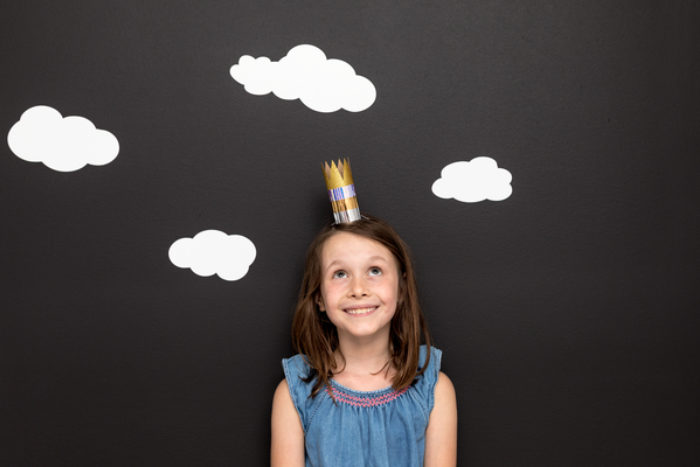 A child wearing a crown made out of a TP roll and colored duck tape.