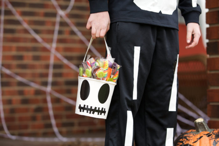 A trick or treat candy bucket decorated as a skeleton skull.