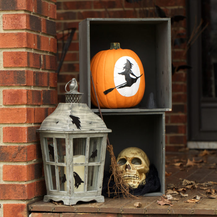 A orange pumpkin decorated with a which silhouette.