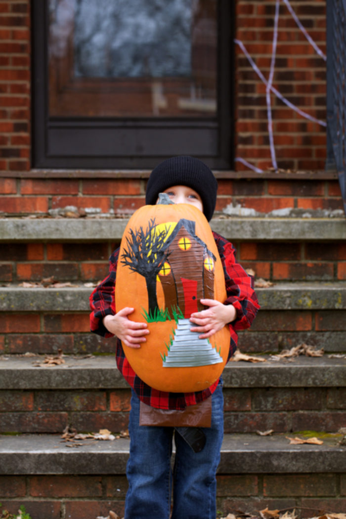 An orange pumpkin with a Haunted house decoration on it.