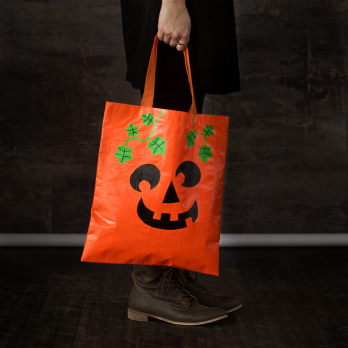 A orange Halloween candy back decorated as a pumpkin.