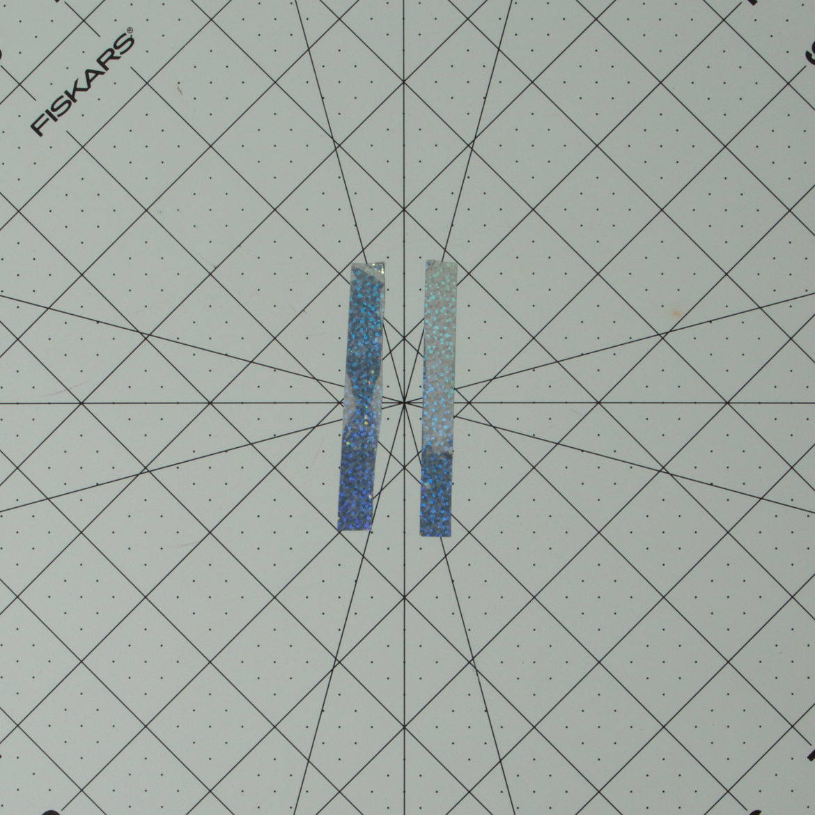 Two thin strips of prism tape the correct size to cover the top and bottom sides of a clothespin