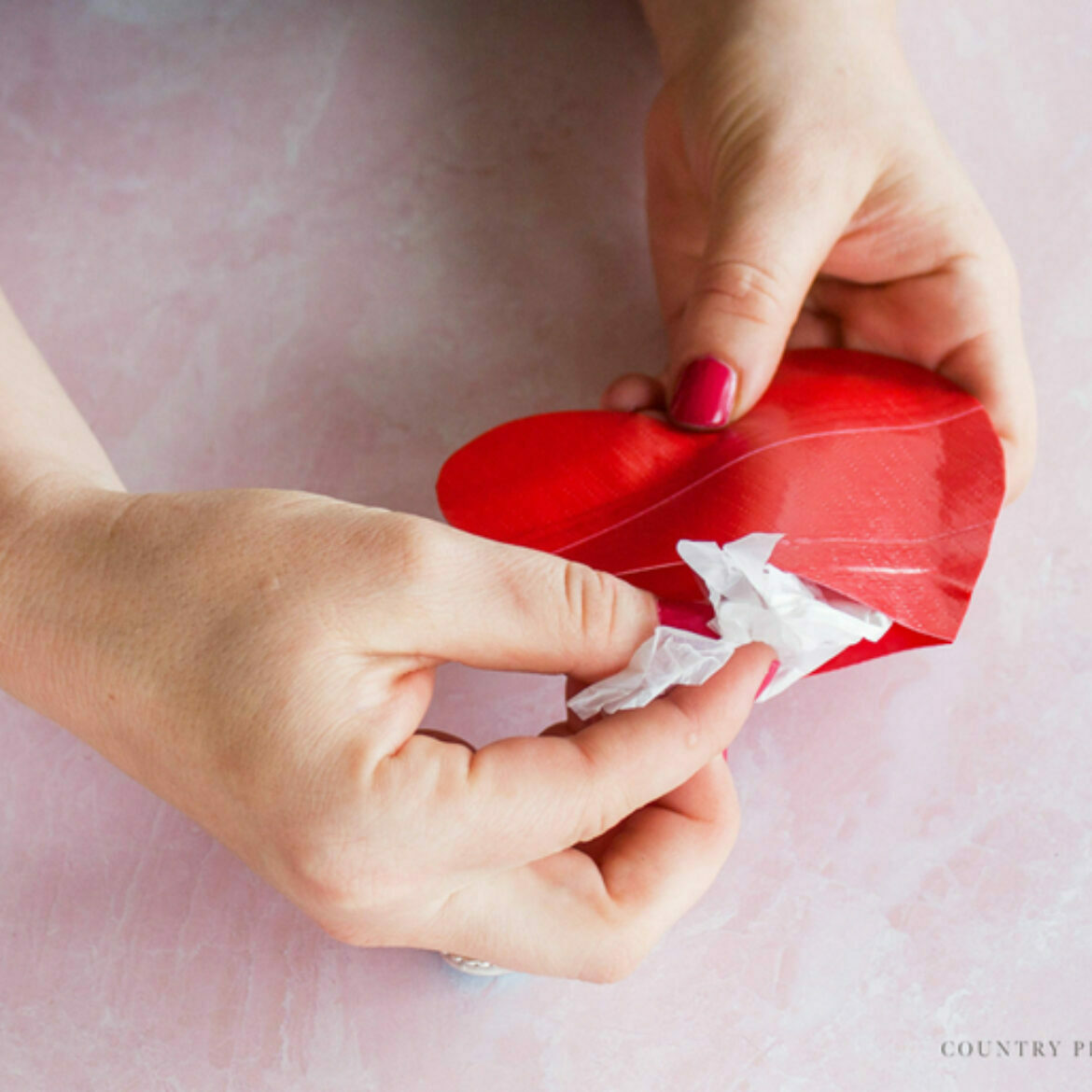 Two hands inserting craft filling into the 3-D duct tape heart