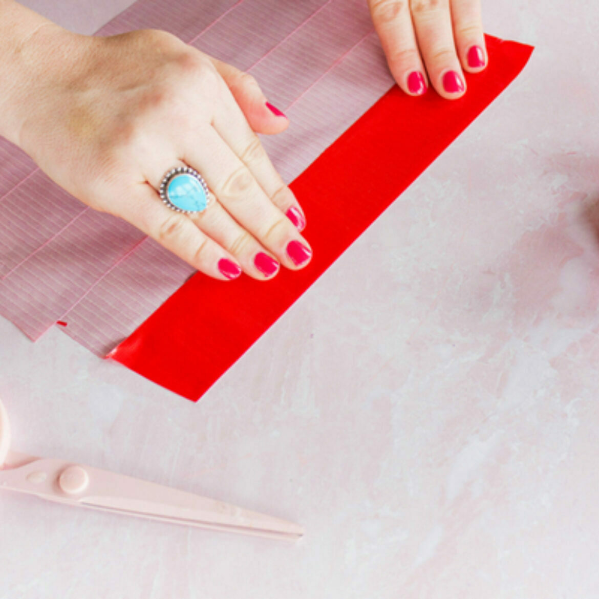 Two hands holding placing horizontally connecting two strips of duct tape on top of each other