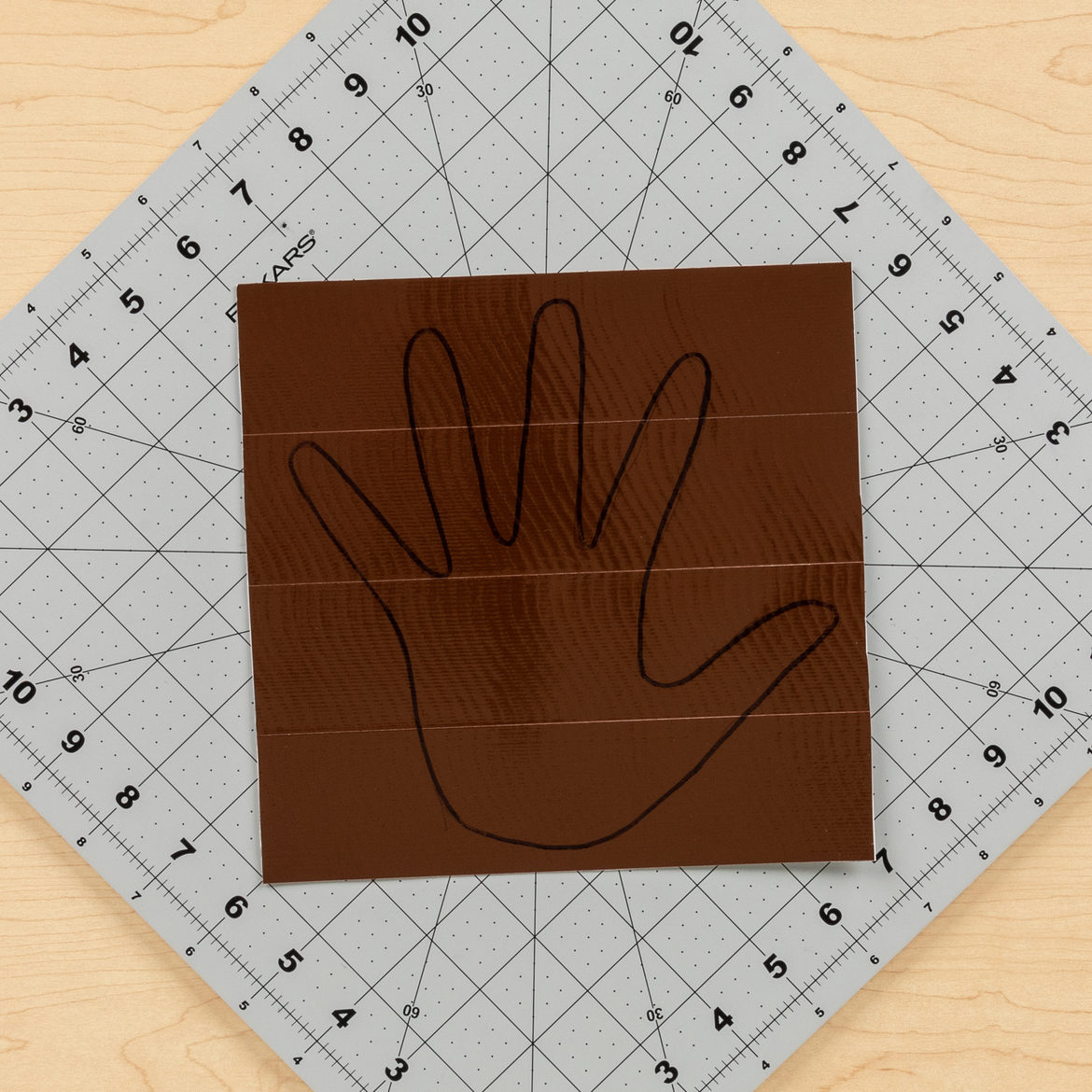 hand print outline drawn on a piece of Brown Duck Tape fabric