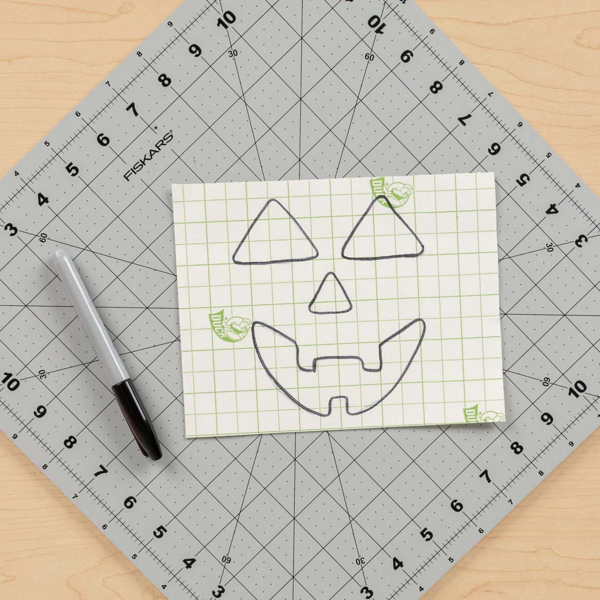 Pumpkin face drawn onto fabric from previous step