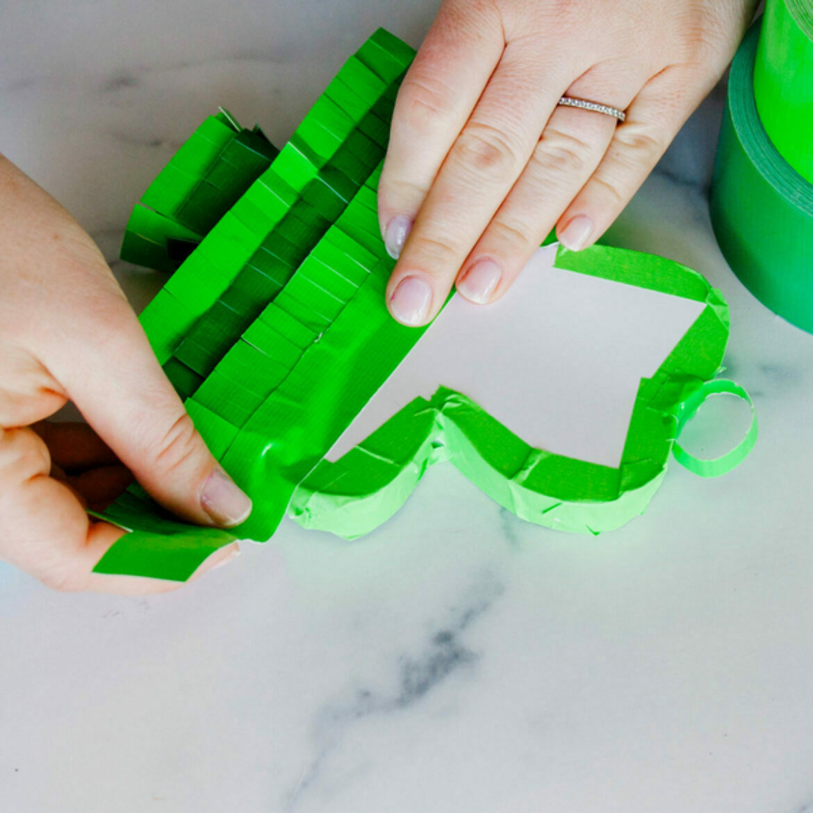 A white marble background with a paper shamrock covered with duct tape fringe