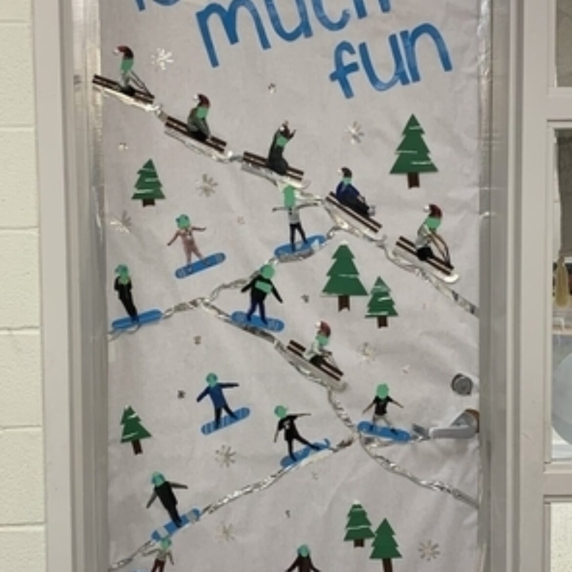 Door decorated with pine trees, cut out people on sleds and snow that says "2nd grade is so much fun"