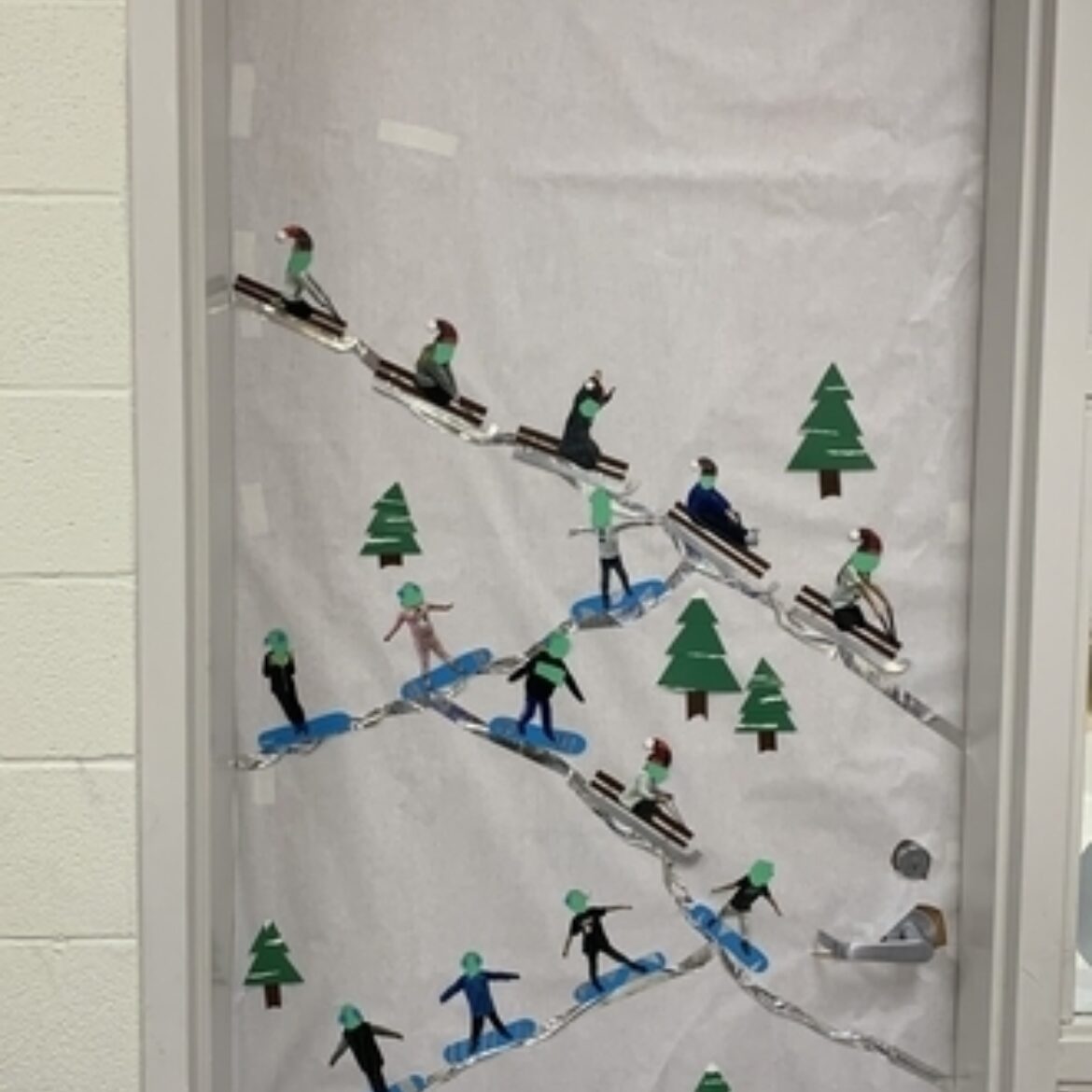 Classroom door with white paper, silver lines to look like mountain tops, pine trees, sleds and snow boards