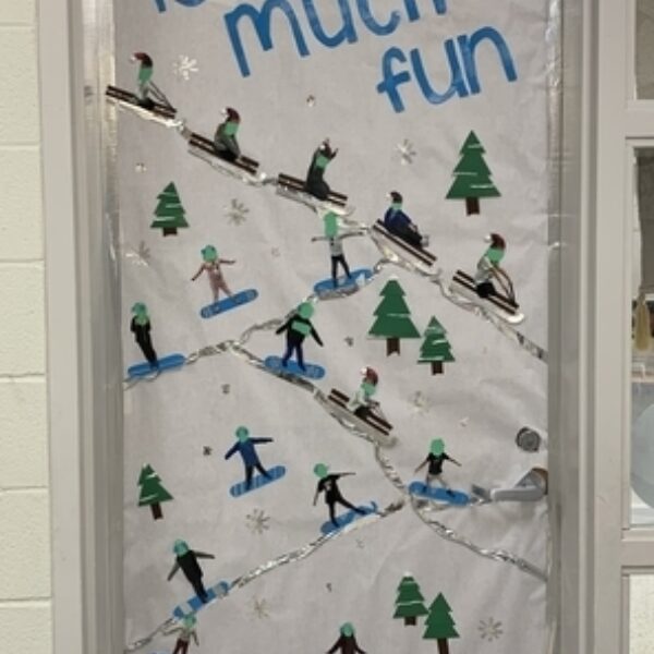 Door decorated with pine trees, cut out people on sleds and snow that says "2nd grade is so much fun"