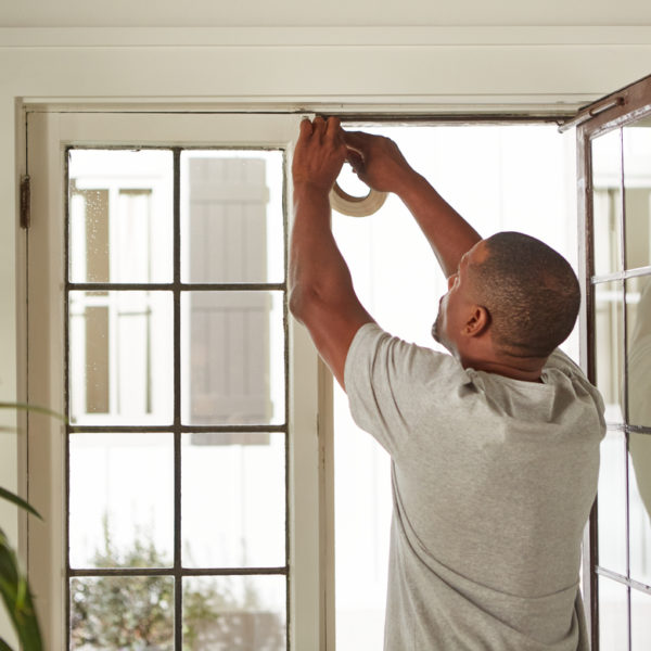 Man installing weatherstripping around a glass door.